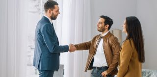 young couple shaking hands with landlord renting a home