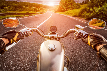 Biker driving a motorcycle rides along the asphalt road. First-person view.