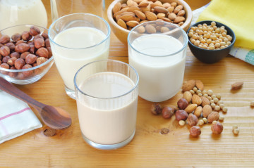 Different vegan milks on a table. Hazelnut, rice, soya and almond milk. Substitute for dairy milk.