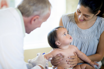 A baby girl with her mother at an appointment with a doctor getting her immunization, vaccines, and shots.