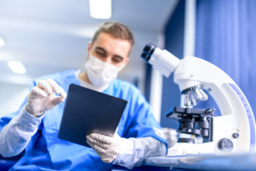 pharmacist working on prescription drugs with modern tablet and microscope