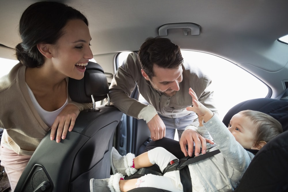 parents getting their baby into a car seat with requirements