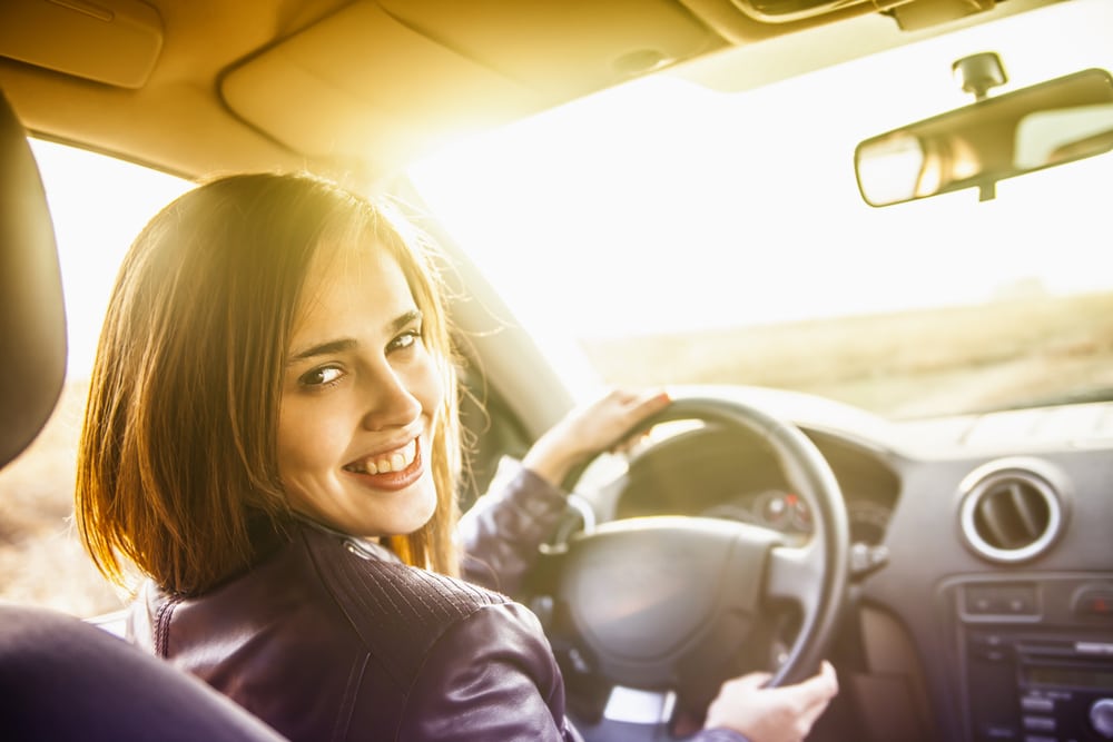 happy young woman driving her used car