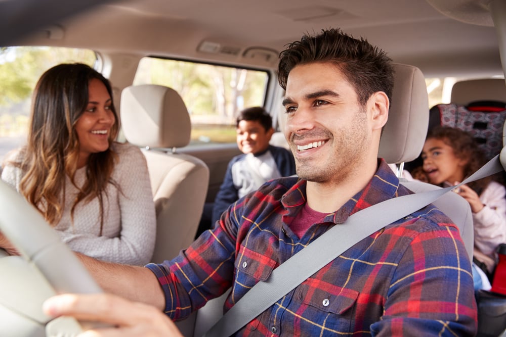 happy hispanic family in a car traveling with kids