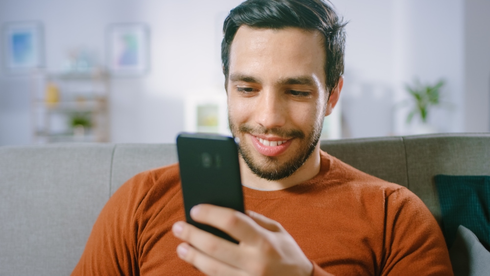 Young Man Uses Smartphone to find car insurance in california