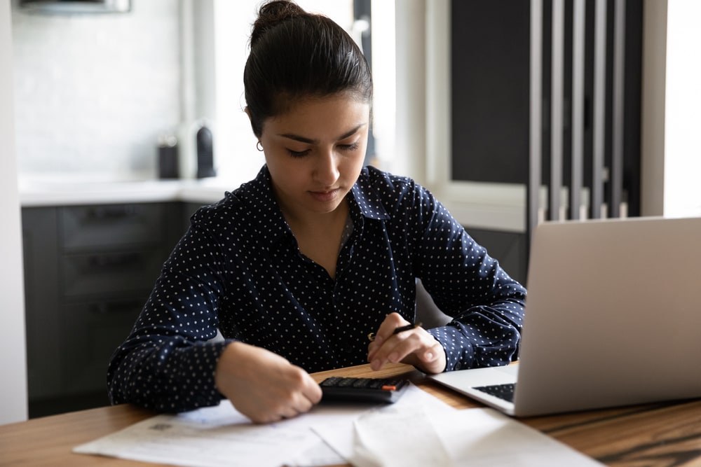 young hispanic woman with laptop and calculator looking for cheap car insurance in california