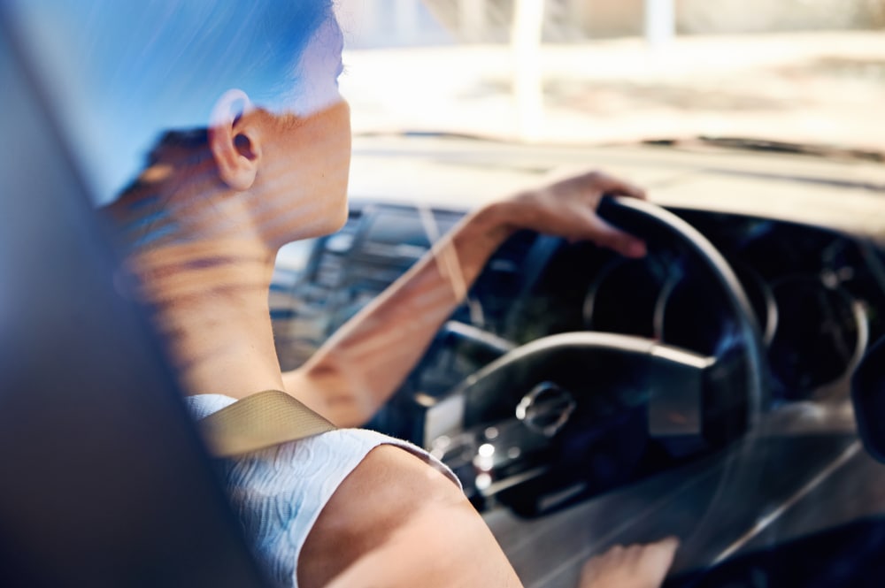 back view of woman driving a car with insurance policy