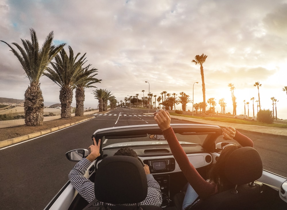 Happy people having fun in convertible car in summer vacation