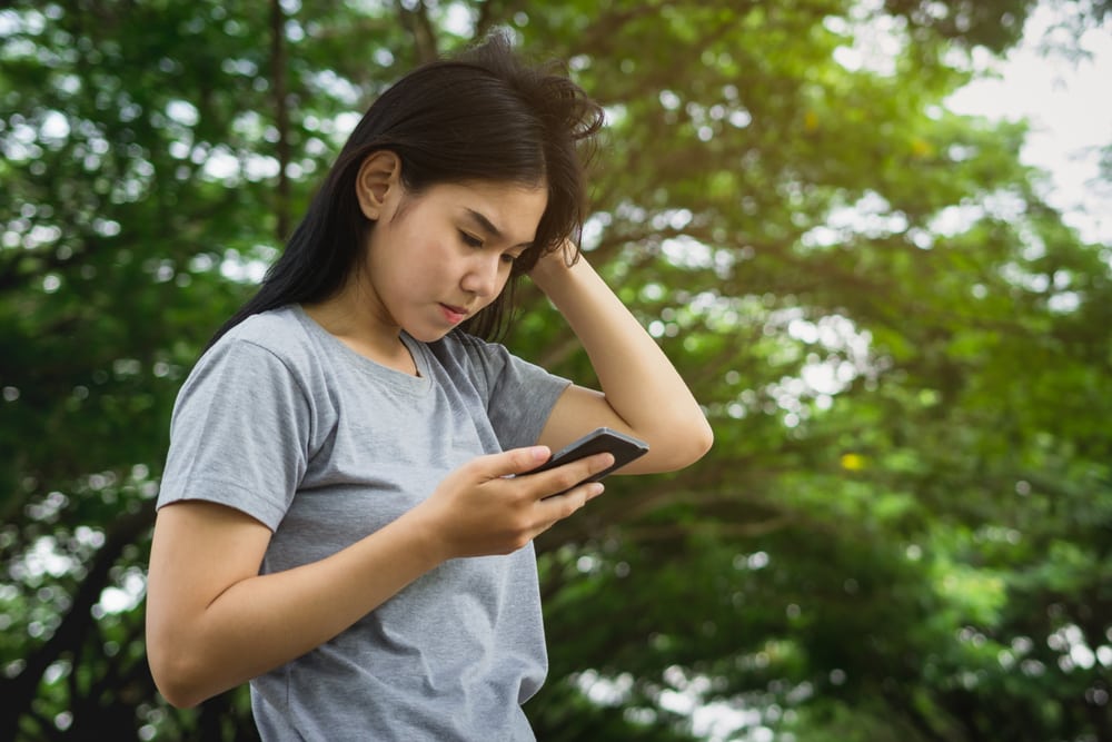 Young Asian woman so serious while using smart phone