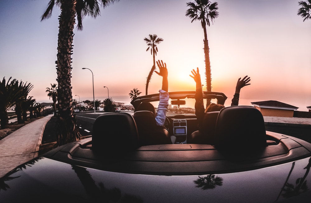 group of people in car with hands up