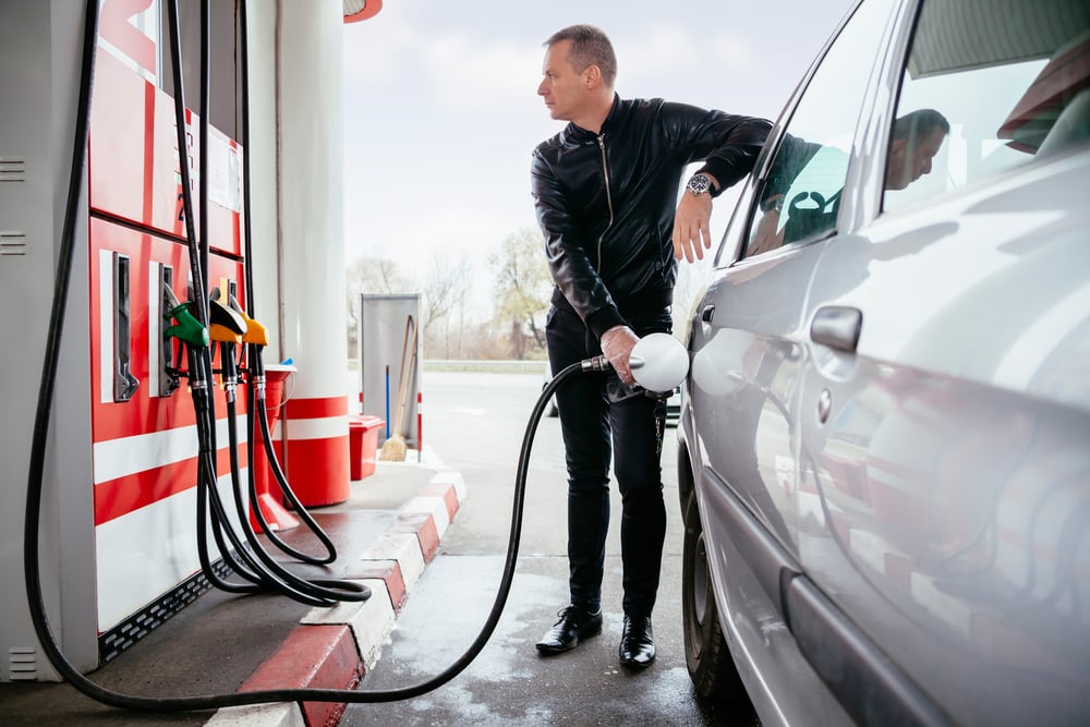 caucasian male pumping gas into car