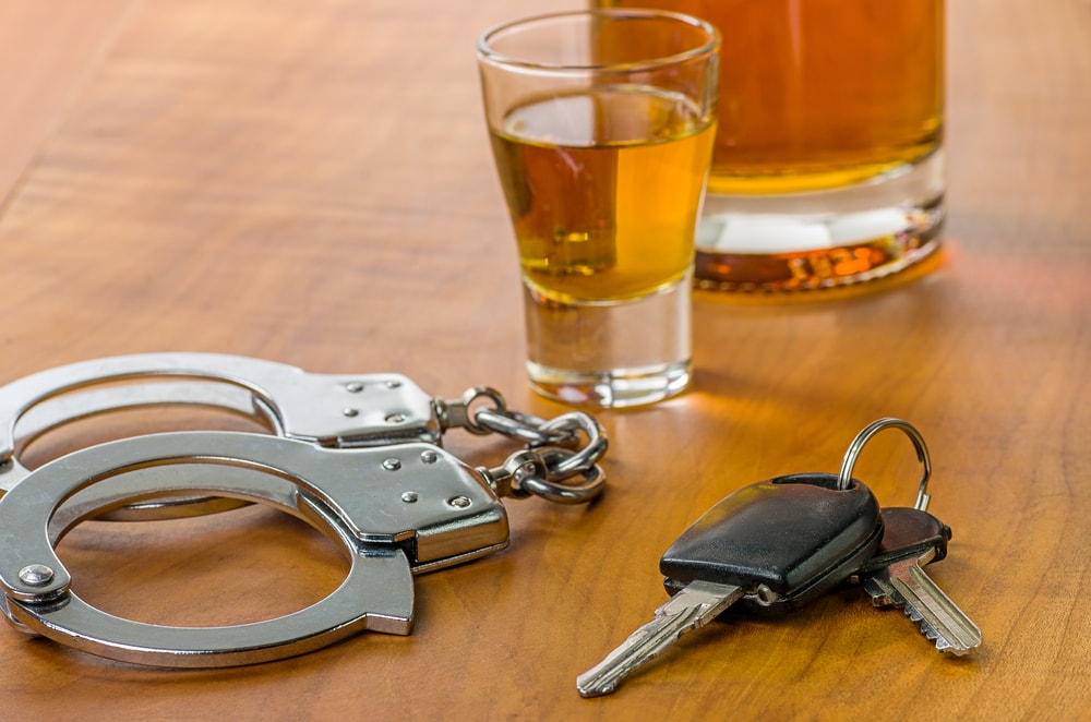 shot glass with handcuffs and car keys next to it