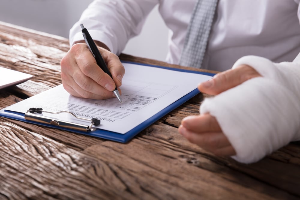 man filling out workers comp form with cast on arm