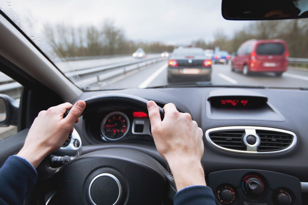 person driving with both hands on steering wheel