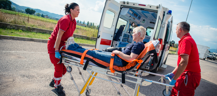 Paramedics moving a woman on a stretcher on a road