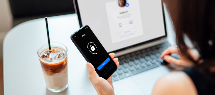 A person drinking coffee and looking at a phone and computer