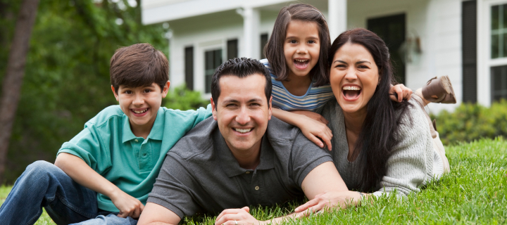 Family posing on grass in front of their house