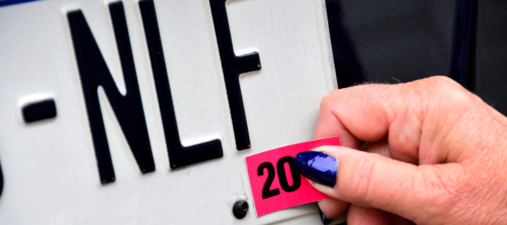 Person adding a registration sticker to a license plate