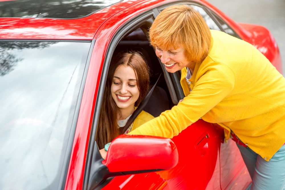 mom standing next to teenage in car